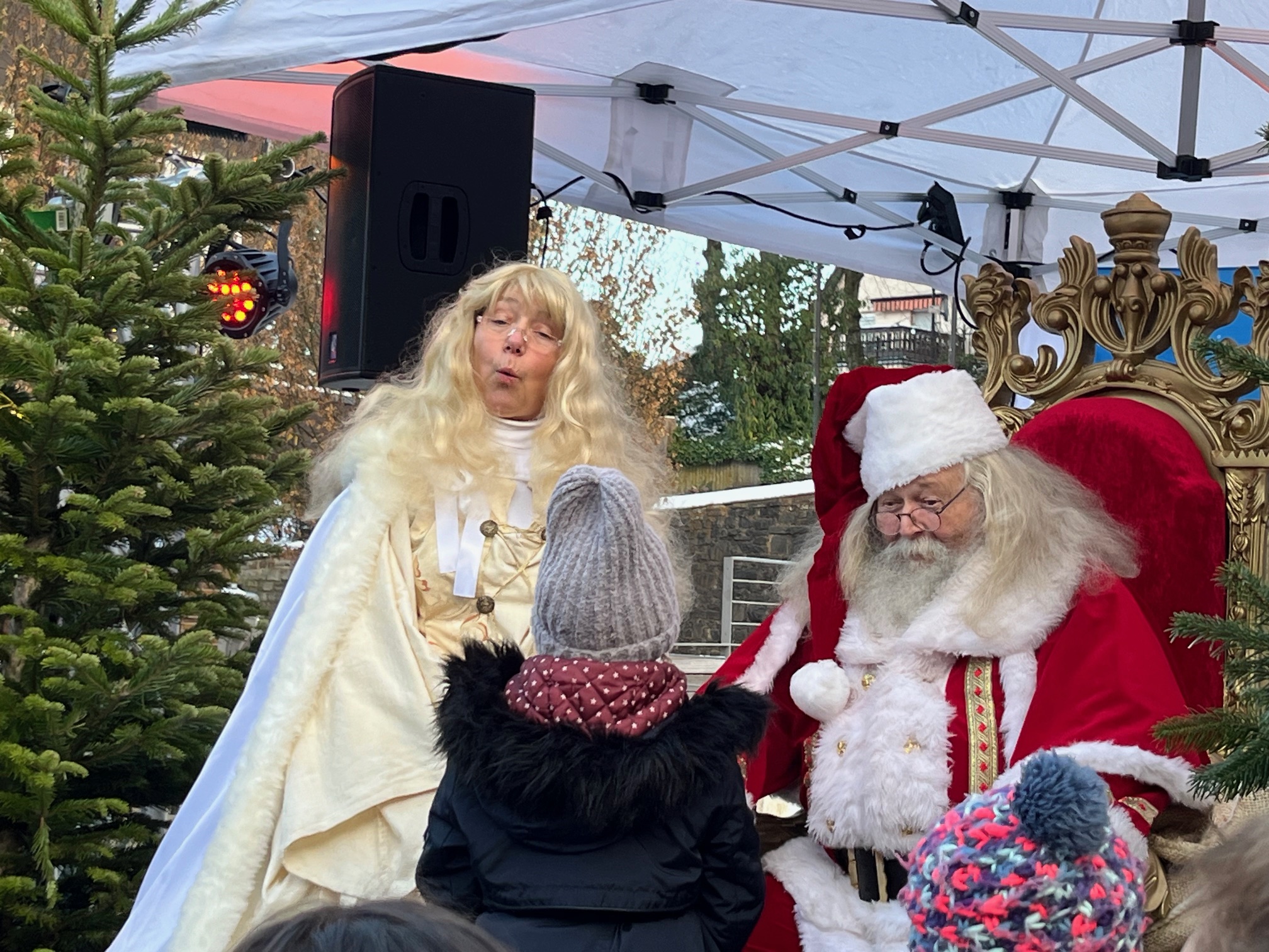 Weihnachtsmann und Christkind bespaßen gemeinsam ein Kinde, das Kind sitzt auf dem Schoß vom Weihnachtsmann